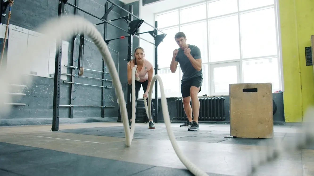 Man and woman exercising with battle ropes