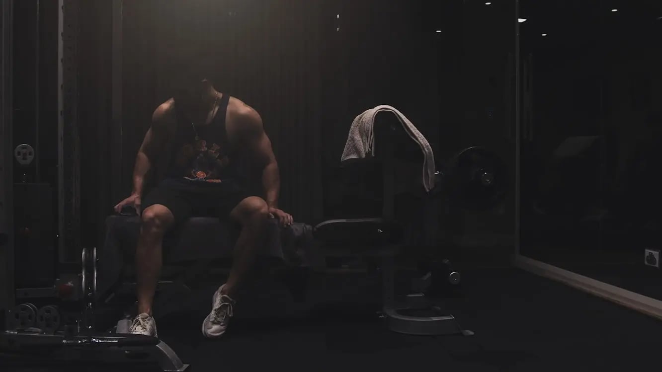 muscular man sitting in a dark
